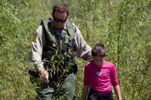 A migrant child is escorted by a U.S. immigration enforcement agent. Credit: cc by 2.0