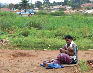 A woman feeds her child in Bwaise - a slum on the outskirts of Kampala. She sits among the remains of local gardens that have been destroyed by floods. / Credit:Andrew Green/IPS