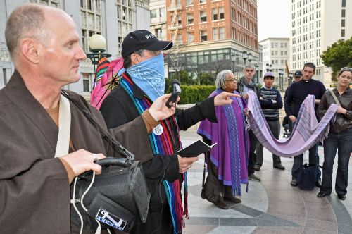 Occupy Interfaith rallies in front of the Oakland City Hall. One pastor wears a mask in solidarity with those banned from the plaza. - Judith Scherr/IPS