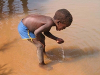 A young boy drinks water from an unclean water source. / Credit:Fidelis Zvomuya