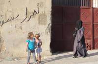 Due bambine osservano una donna a passeggio coperta dal velo integrale ad Aleppo, Siria. Shelly Kittleson/IPS