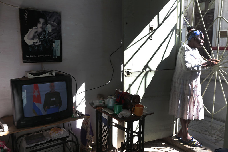 Havannalainen nainen seisoo asuntonsa ovella samalla kun presidentti puhuu televisiossa. Kuva: Jorge Luis Baños/IPS