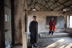 Shugufta Barkat, a former teacher, and her brother Rasikh Barkat, a former student, stand the charred remains of the Nasirabad Government High School in Kulgam – one of the many schools in India’s Kashmir that have been recently burnt down. Credit: Stella Paul/IPS