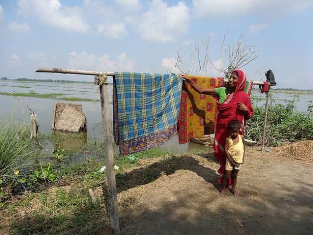 A woman dries blankets after her home went underwater for five days in one of the villages of the Morigaon district, India. Credit: Priyanka Borpujari/IPS