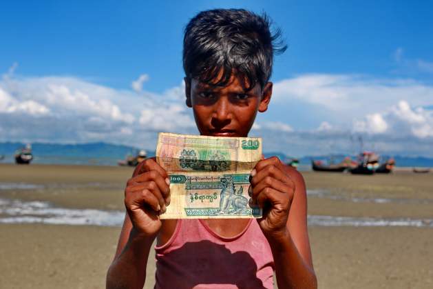 A Rohingya boy shows his Myanmar currency at Shahparir Dwip in Cox's Bazar. Credit: Farid Ahmed / IPS