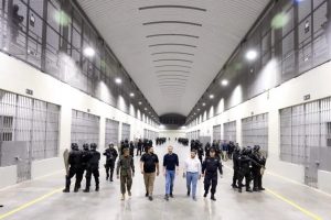 Salvadoran President Nayib Bukele (C) tours the facilities of the Terrorism Confinement Center (Cecot) in January, when through a video he showed for the first time the interior of the new mega-prison, built to hold 40,000 gang members. Some 65,000 people accused of belonging to the gangs or maras have been arrested since the state of emergency was declared in March 2022. CREDIT: Presidency of El Salvador - Despite serious allegations by the US justice system that two officials of the government of Nayib Bukele reached a secret pact with gangs to keep the homicide rate low, the Salvadoran president seems to have escaped unscathed for now, without political costs