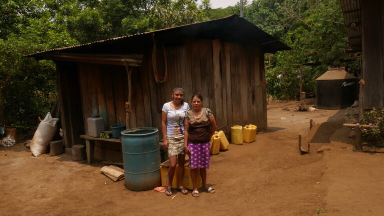 Gumersinda Crespo (R) and her daughter Marcela stand next to the kitchen of their house in the Jocote Dulce canton in eastern El Salvador, an area with a chronic water crisis because it is located in the Central American Dry Corridor, where the shortage of rainfall makes life complicated. Almost every household in this remote location has various plastic containers and tanks to capture rain. CREDIT: Edgardo Ayala/IPS