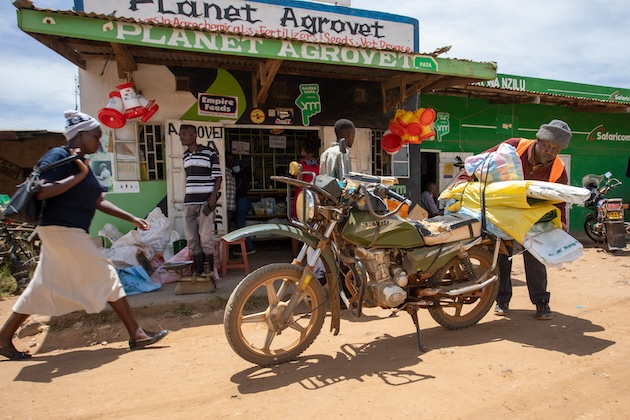 Ngumbi Ndambuki, a Kenya Cereal Enhancement Programme (KCEP) farmer, packs his cereal storage bags on his motorbike. He purchased the bags from Planet Agrovet, an agro-dealer based in Kathonzweni, Makueni county. IFAD aims to create resilient smallholder farmers. Credit: IFAD/ Isaiah Muthuirg