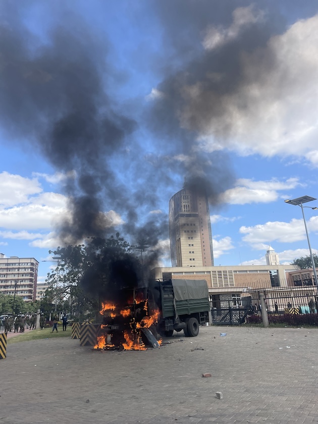 A police vehicle set on fire by angry protesters as they sought entry into the national parliament in Nairobi. Credit: Robert Kibet/IPS