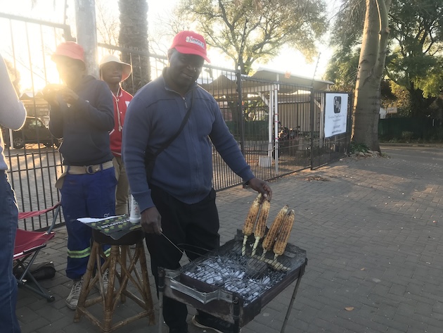 Edward Phiri cooking mealies (maize) on an open fire at his vegetable stall in a busy street in Windsor West, Johannesburg. Edward, mentioned how expensive mealies had become in the last few months and that he was the only vegetable stall selling cooked maize. All the other many stalls (at least 15 in a small but densely populated area had closed down. Credit: Kevin Humphrey/IPS