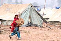 Kashmala Bibi sorride mentre porta una scatola di provviste alla sua tenda. Ashfaq Yusufzai/IPS